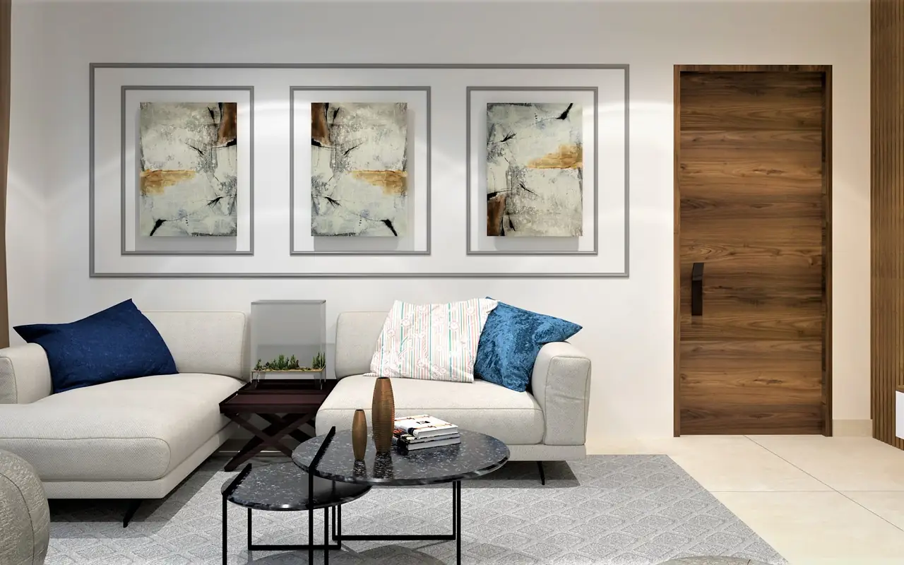 A pale sectional beneath a triptych, on a soft wool rug.